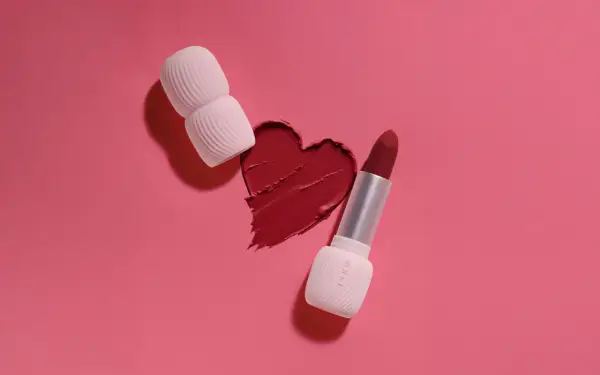 Un cuore di rossetto rosso, con un rossetto e un applicatore, mostra diversi tipi di rossetto.